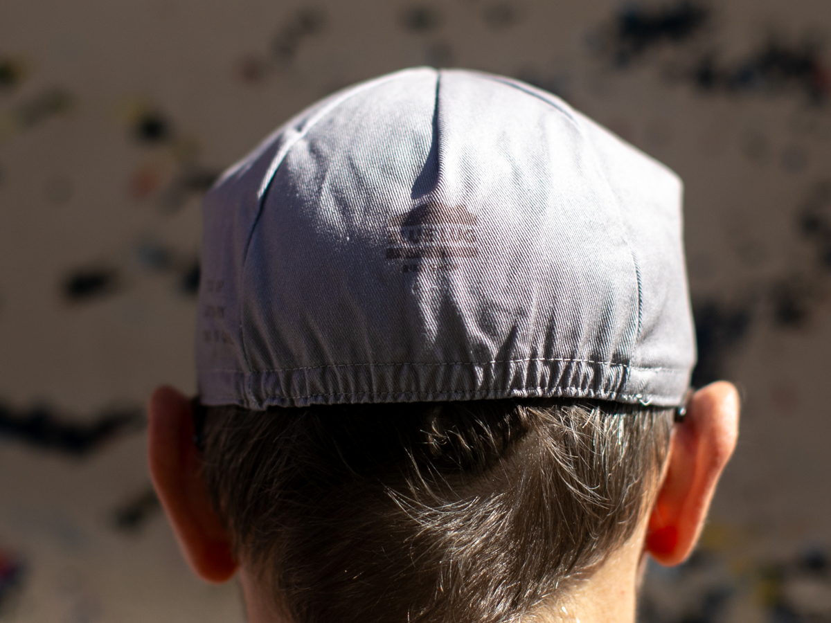 Vue arrière de la casquette de cyclisme Blue Lug Muji coloris gris, montrant la calotte unie, le bord élastiqué et le discret logo Blue Lug à l'arrière.