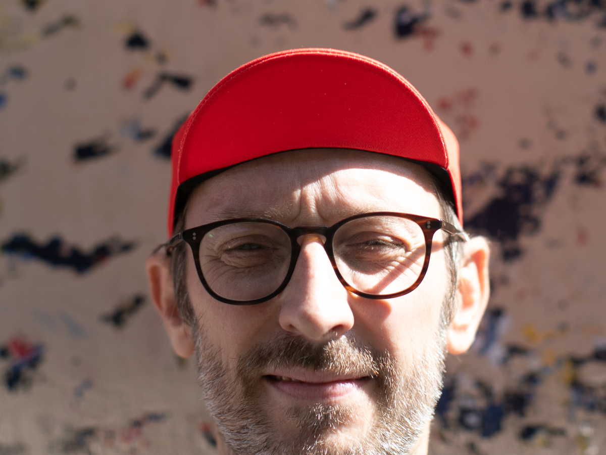 Casquette de cyclisme Blue Lug Jump and Dash rouge portée visière relevée, vue de face. Les panneaux rouges unis et la silhouette classique de la casquette cycliste sont visibles.