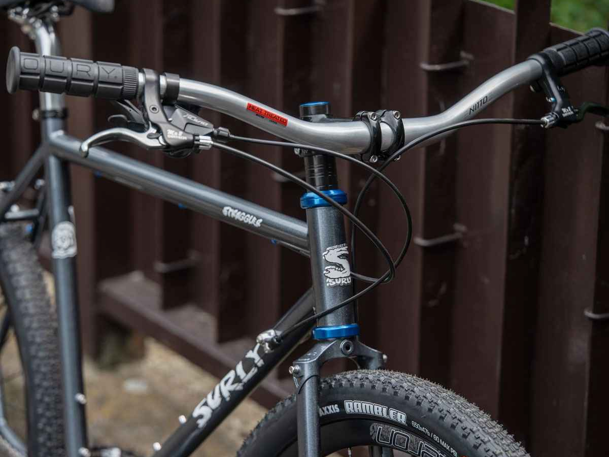 Guidon Nitto Sync XL argent monté sur un VTT acier avec poignées Oury et fourche Surly