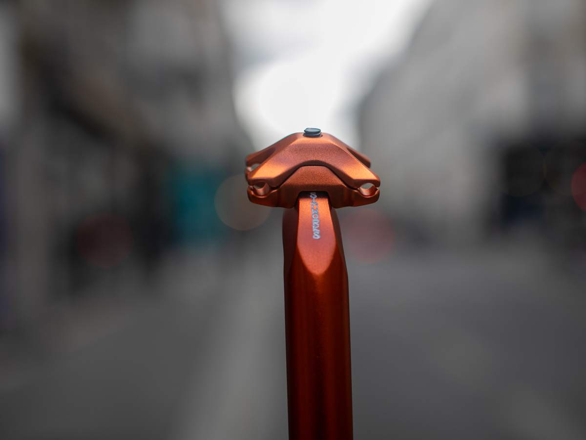 SimWorks Beatnik Sunrise seat post — close-up of the saddle clamp head in Sunrise orange showing the hand-engraved SimWorks logo on the post